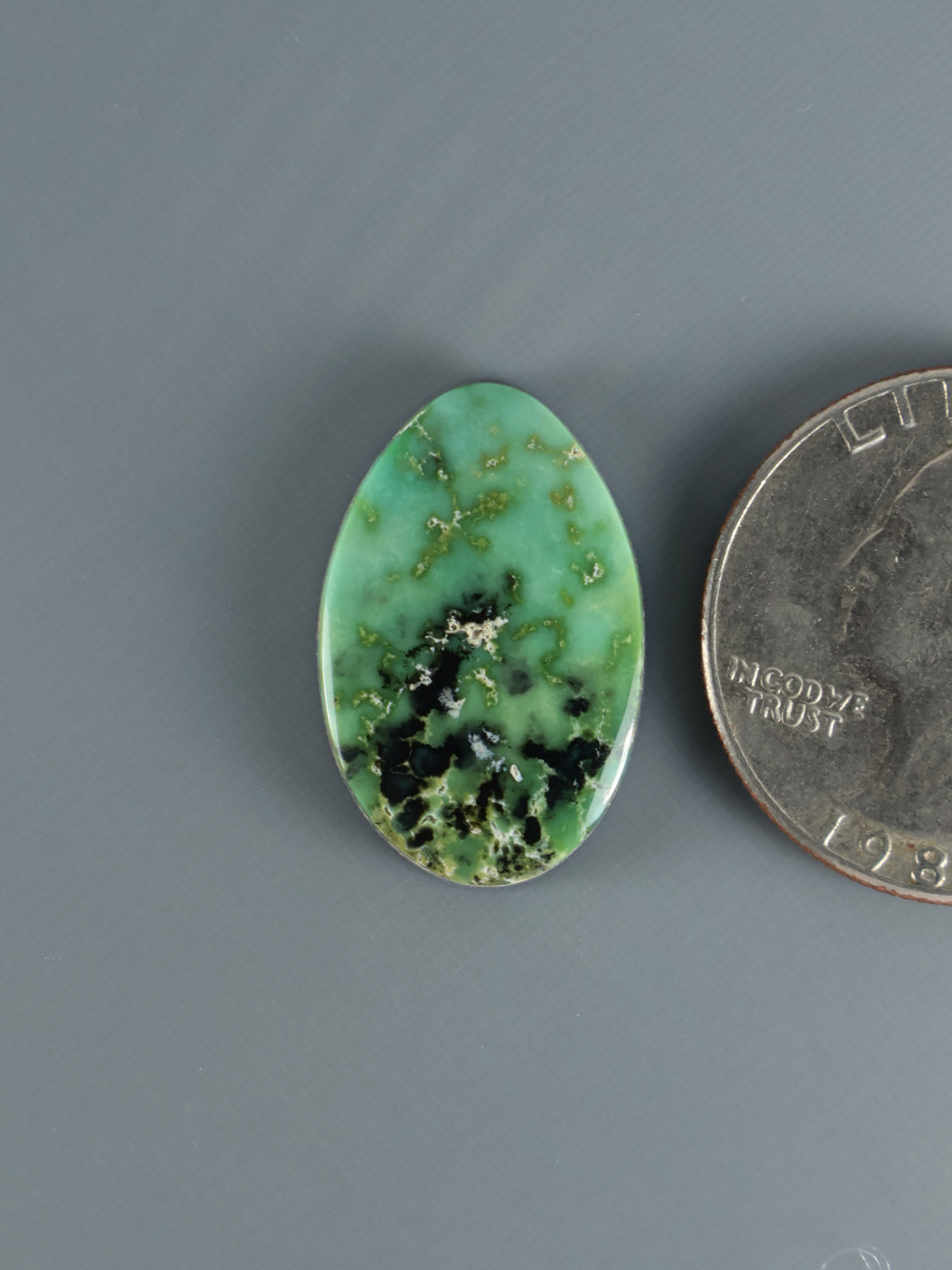 Oval green variscite cabochon with dark matrix veining