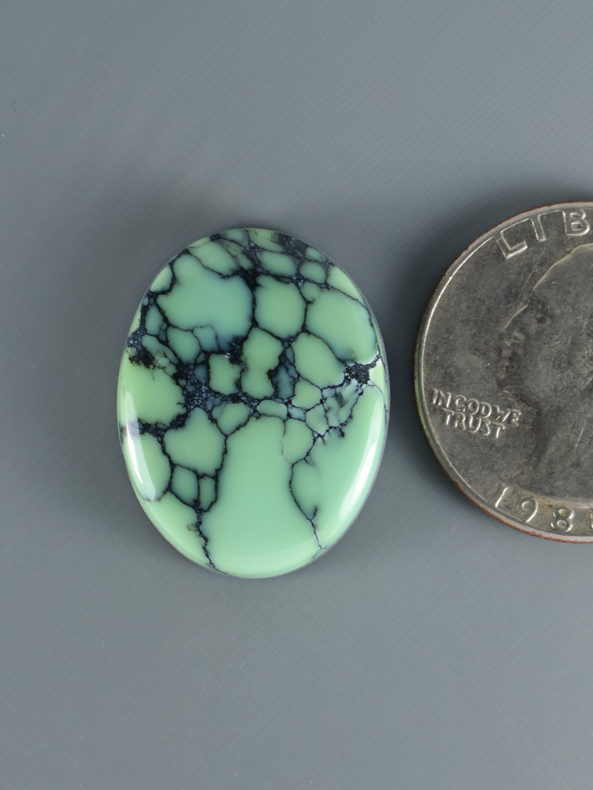 Oval mint-green variscite cabochon with dark vein web pattern