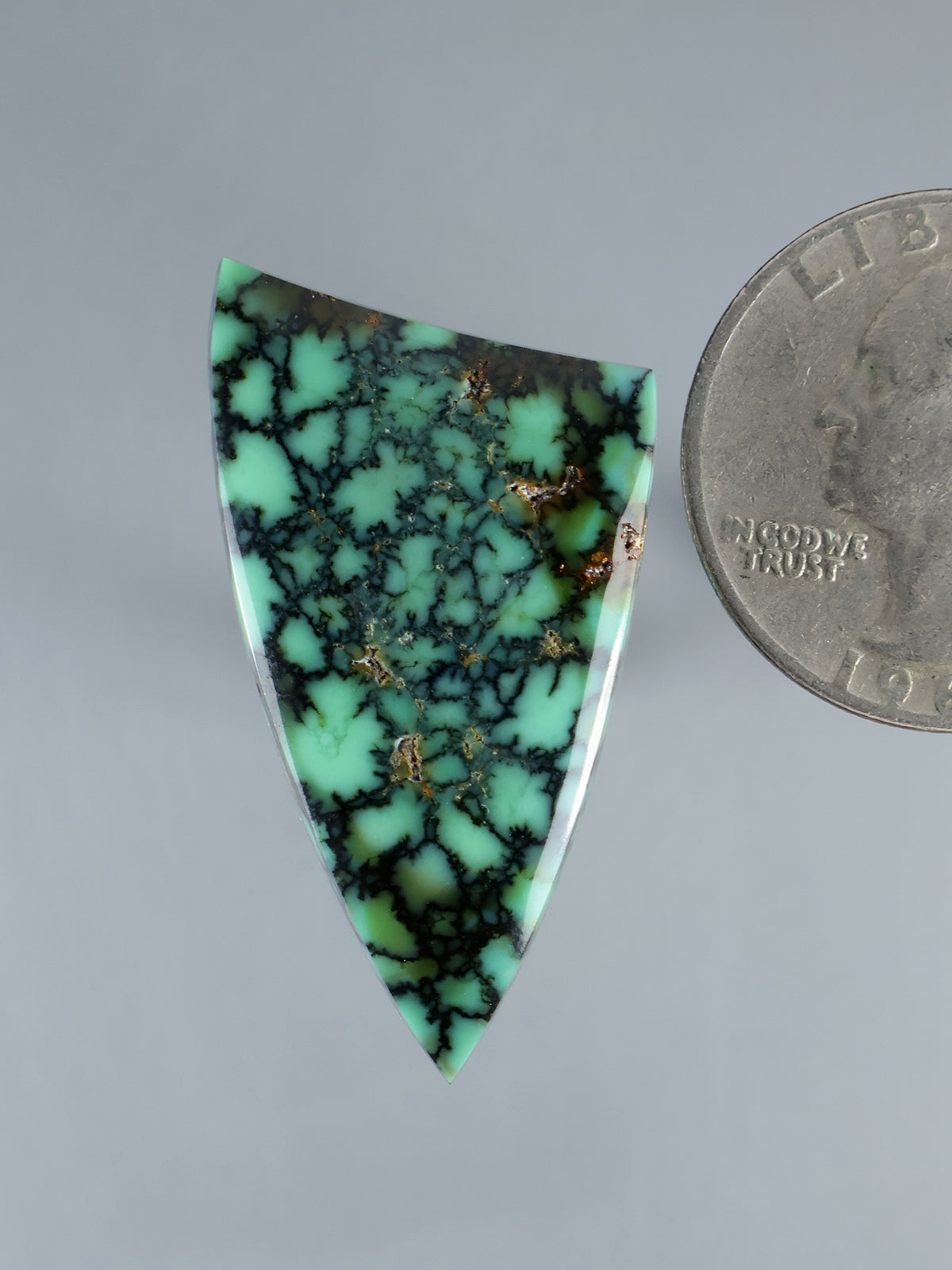 Triangular green variscite cabochon with dark web veins and small gold flecks