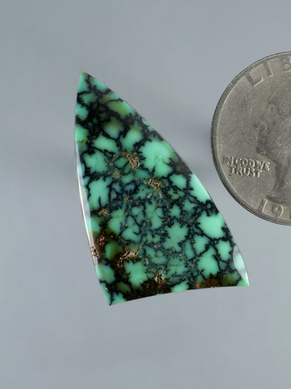 Triangular green variscite cabochon with black veining and tiny gold flecks, angled