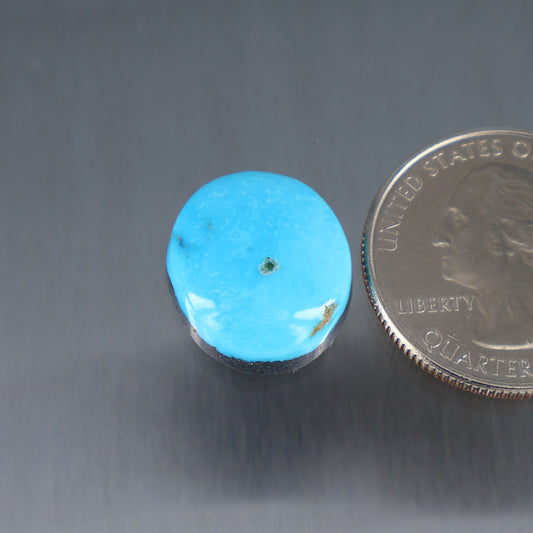 Round turquoise cabochon with small metal bezel, gemstone close-up
