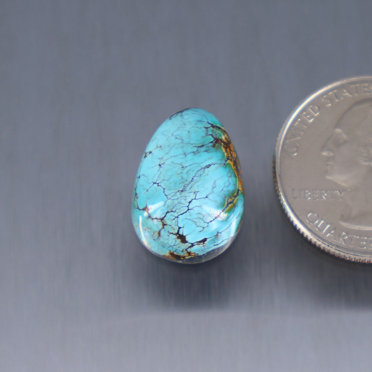 Turquoise cabochon with blue-green color and dark veining, teardrop shape