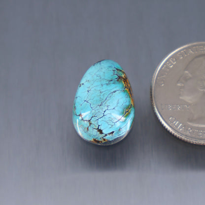 Turquoise cabochon with blue-green color and dark veining, teardrop shape