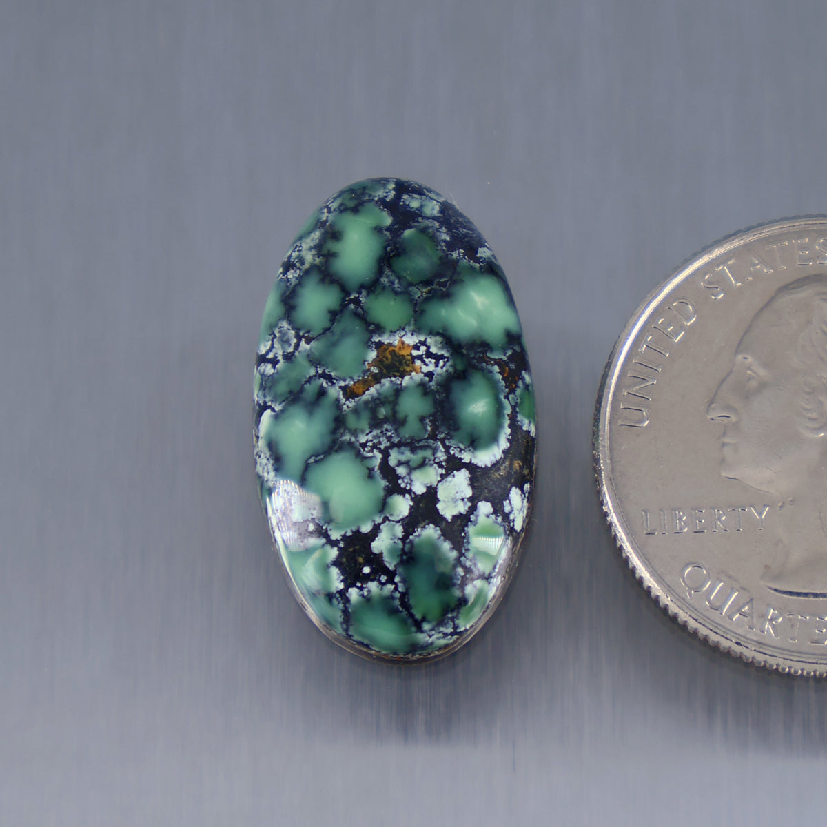 Oval turquoise cabochon gemstone with dark green matrix veining