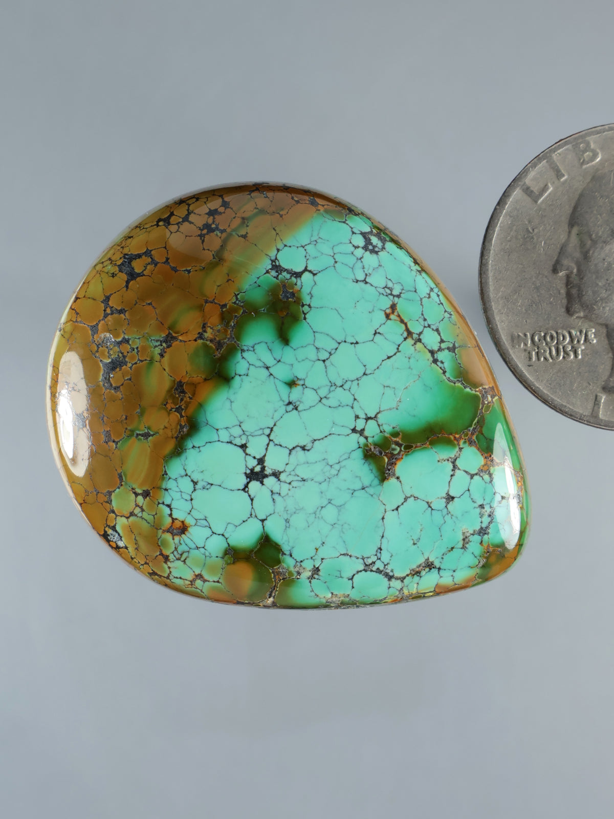 Turquoise teardrop cabochon gemstone with brown streaks and cracked stone pattern, domed