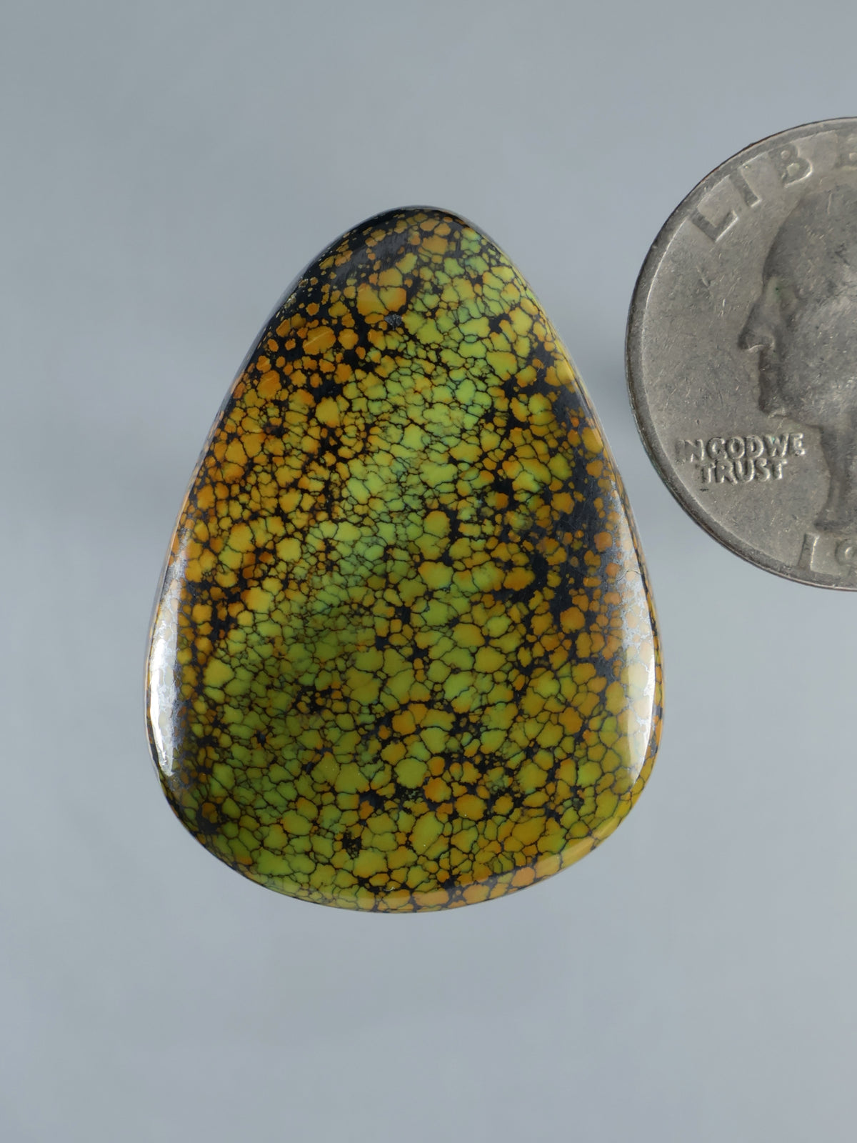 Turquoise cabochon gemstone with yellow-gold webbed pattern, teardrop shape