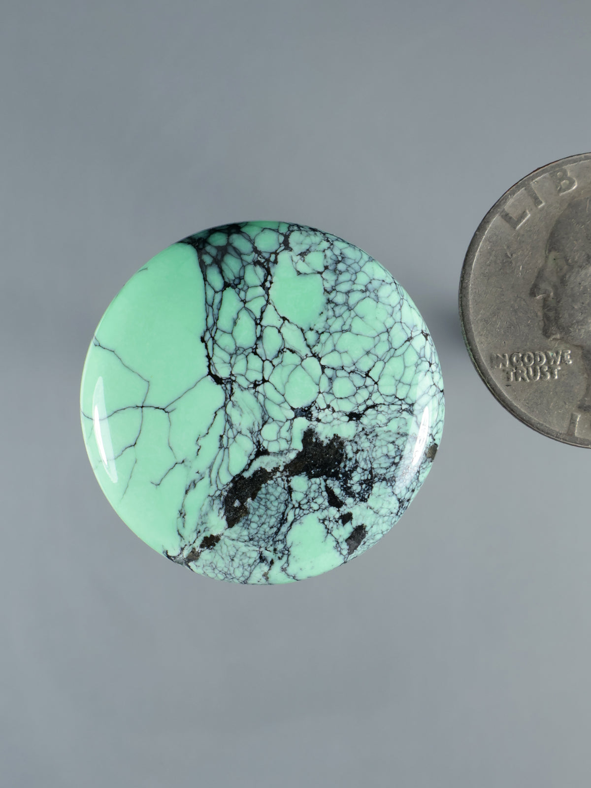 Variscite cabochon gemstone, mint green with black matrix patch and crackle web, polished oval
