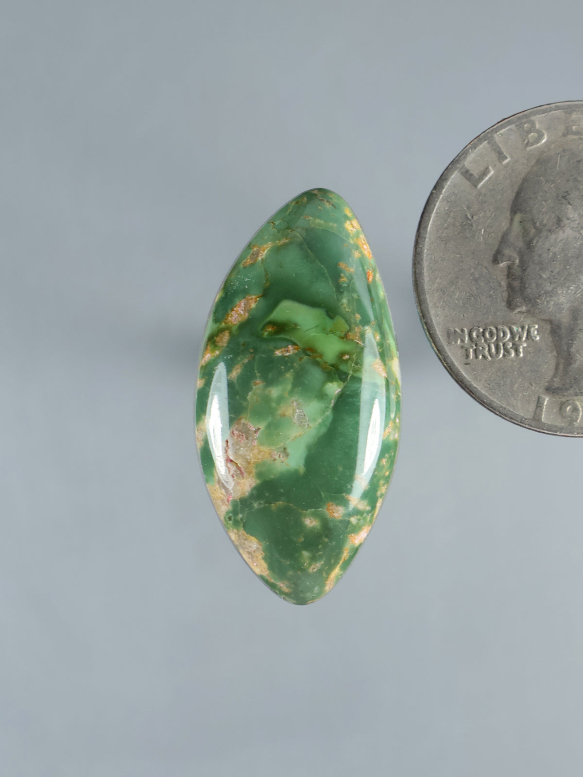 Oval green turquoise cabochon gemstone with natural matrix and polished shine