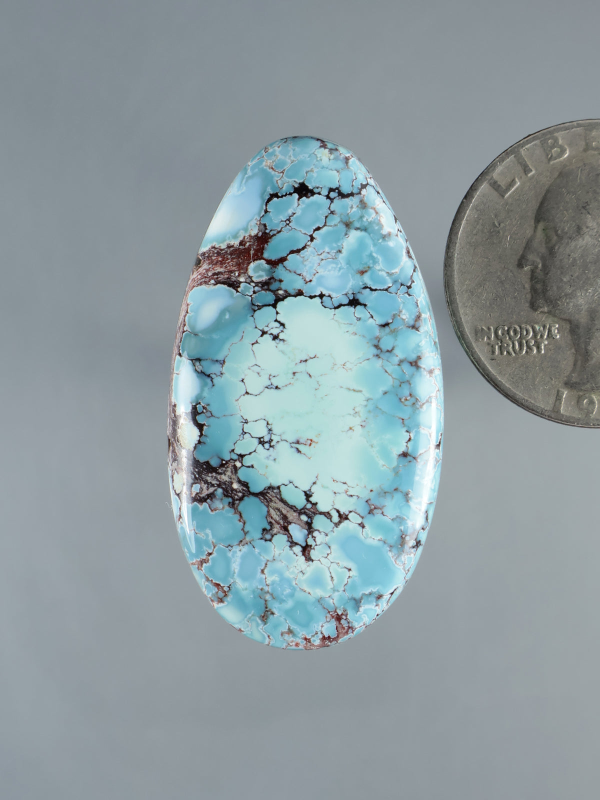 Oval turquoise-blue gemstone cabochon with brown matrix veining