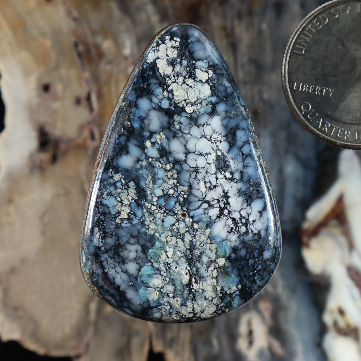 Blue teardrop cabochon gemstone with white web-like veining, polished surface