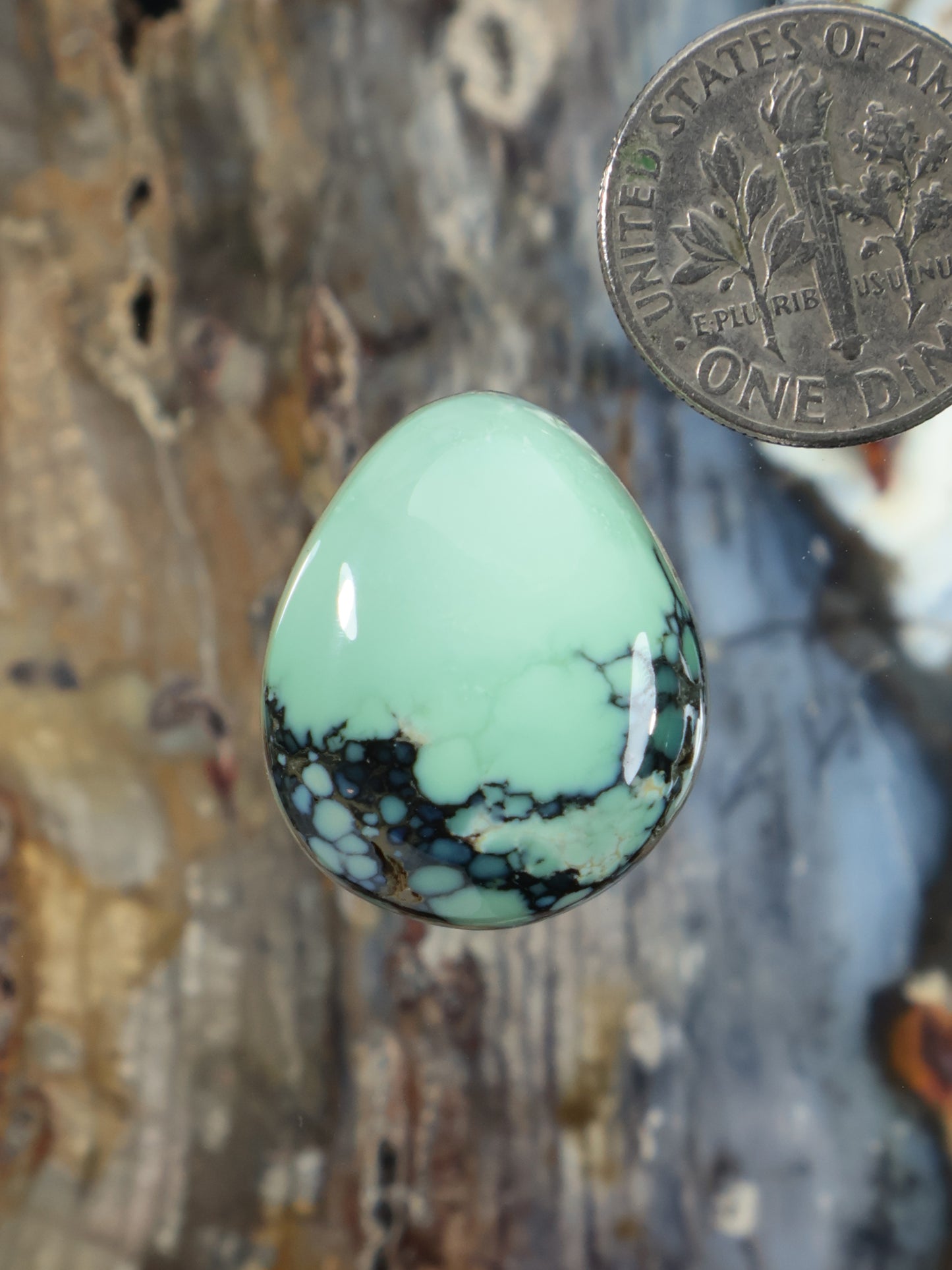 Mint green variscite cabochon teardrop in silver bezel, visible dark matrix