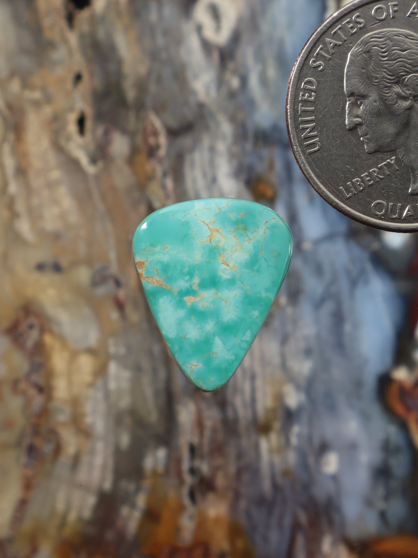 Turquoise cabochon gemstone, teardrop shape, polished with natural matrix pattern.
