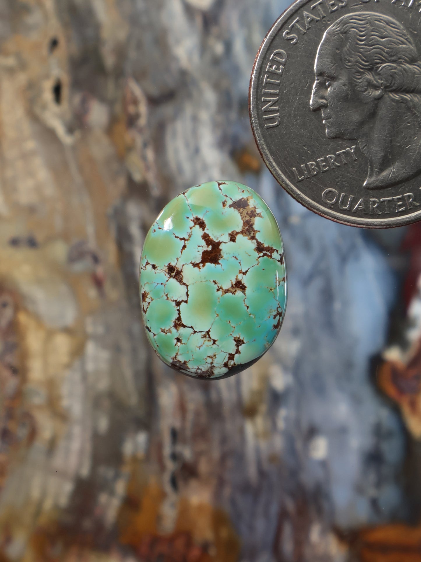 Oval turquoise cabochon gemstone with green-blue color and dark matrix veining