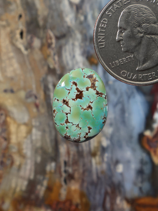Oval turquoise cabochon gemstone with green-blue color and dark matrix veining