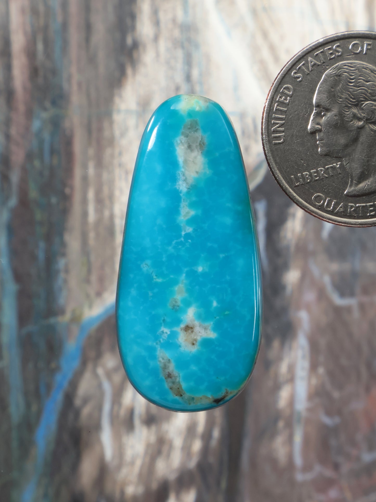 Turquoise cabochon gemstone, teardrop oval shape with natural veining.