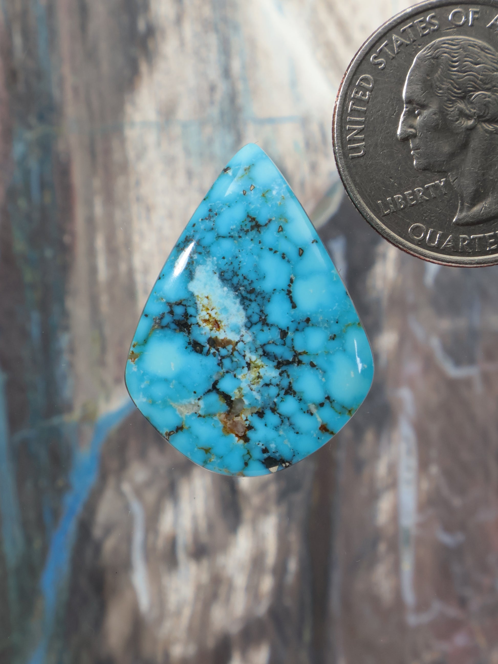 Blue turquoise cabochon in a teardrop shape with dark natural matrix