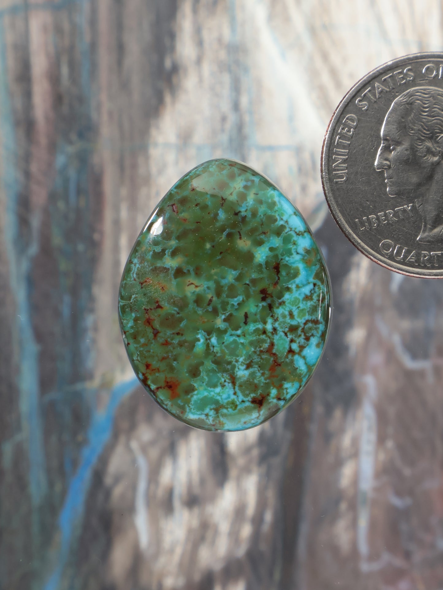 Oval polychrome turquoise cabochon, green-blue with red speckling and smooth dome