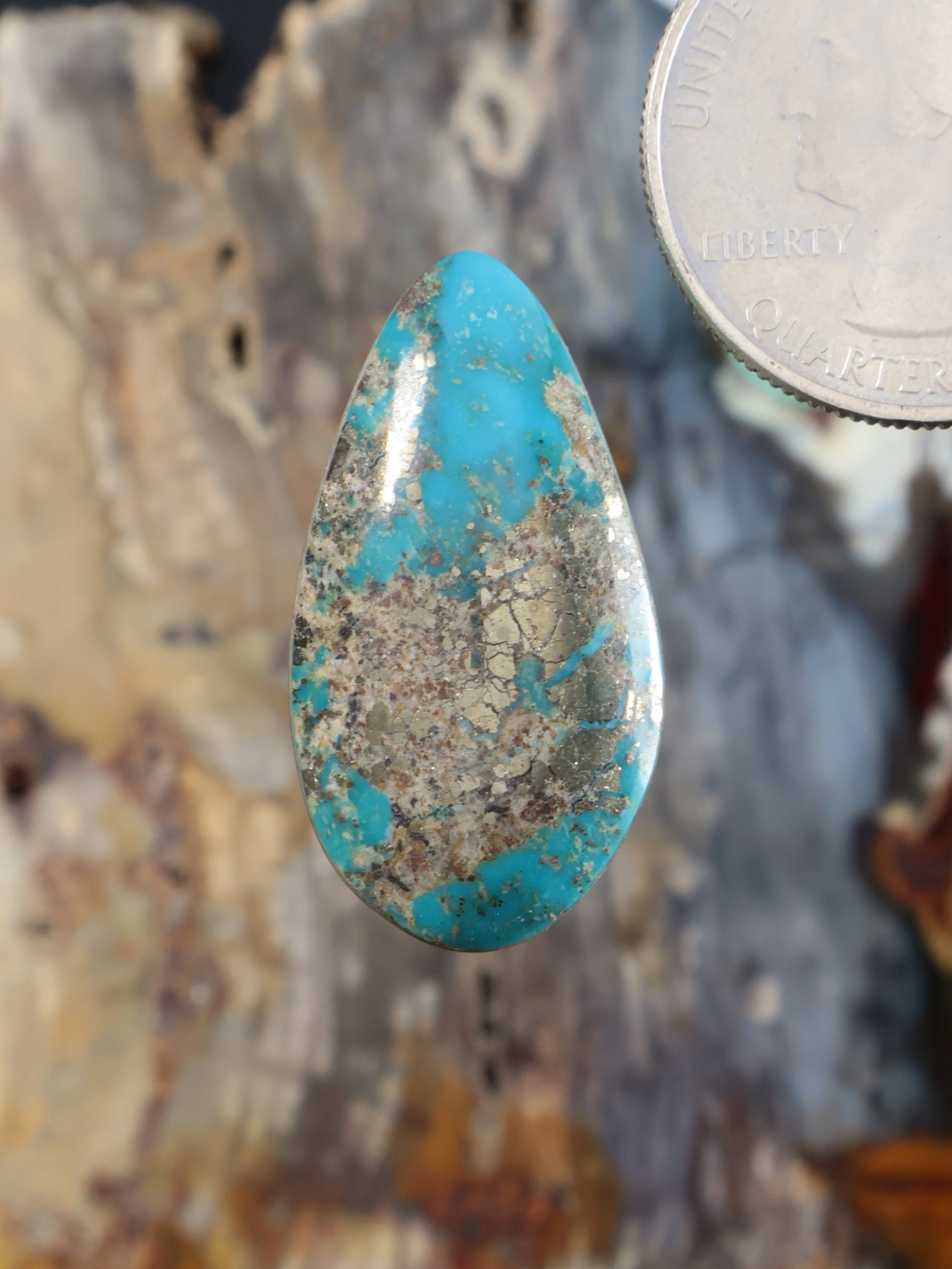 Turquoise cabochon gemstone with teardrop shape and mottled blue-green matrix