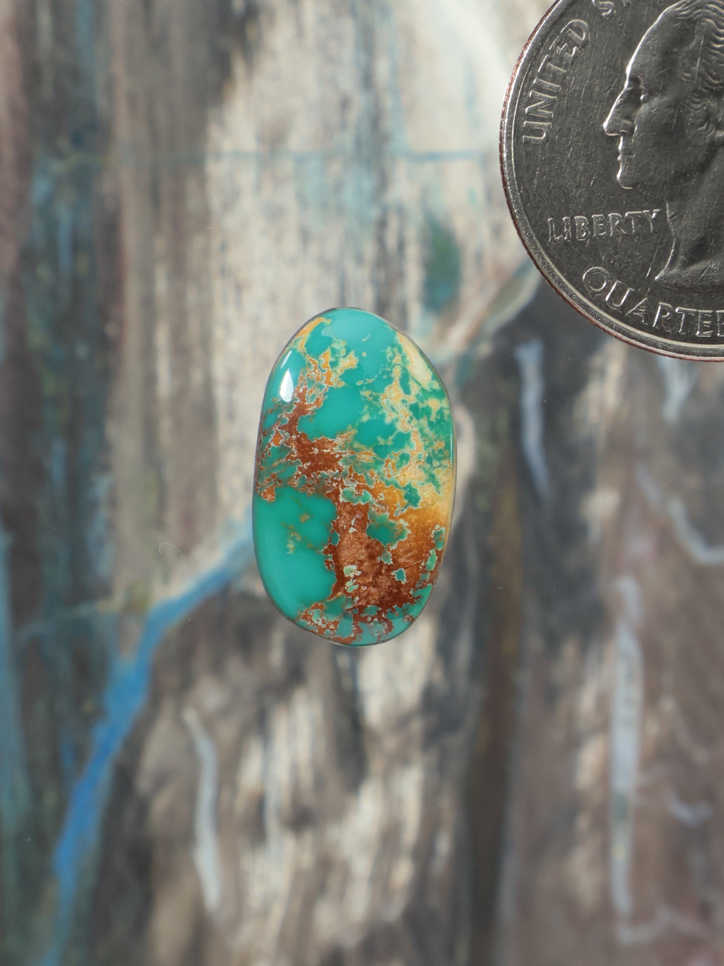 Oval turquoise cabochon gemstone with green-blue body and gold-brown matrix