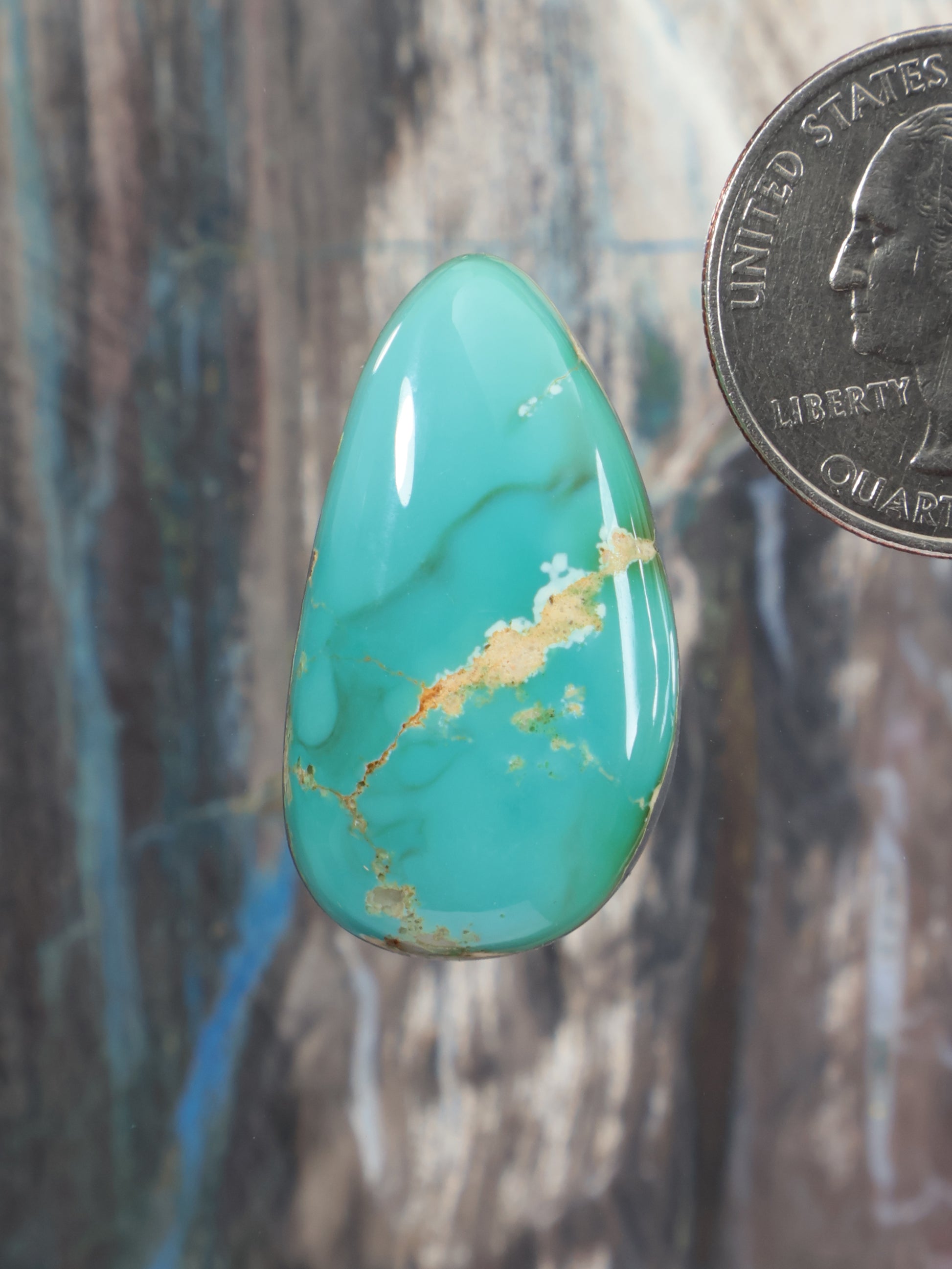 Turquoise teardrop cabochon gemstone with gold veining, polished surface