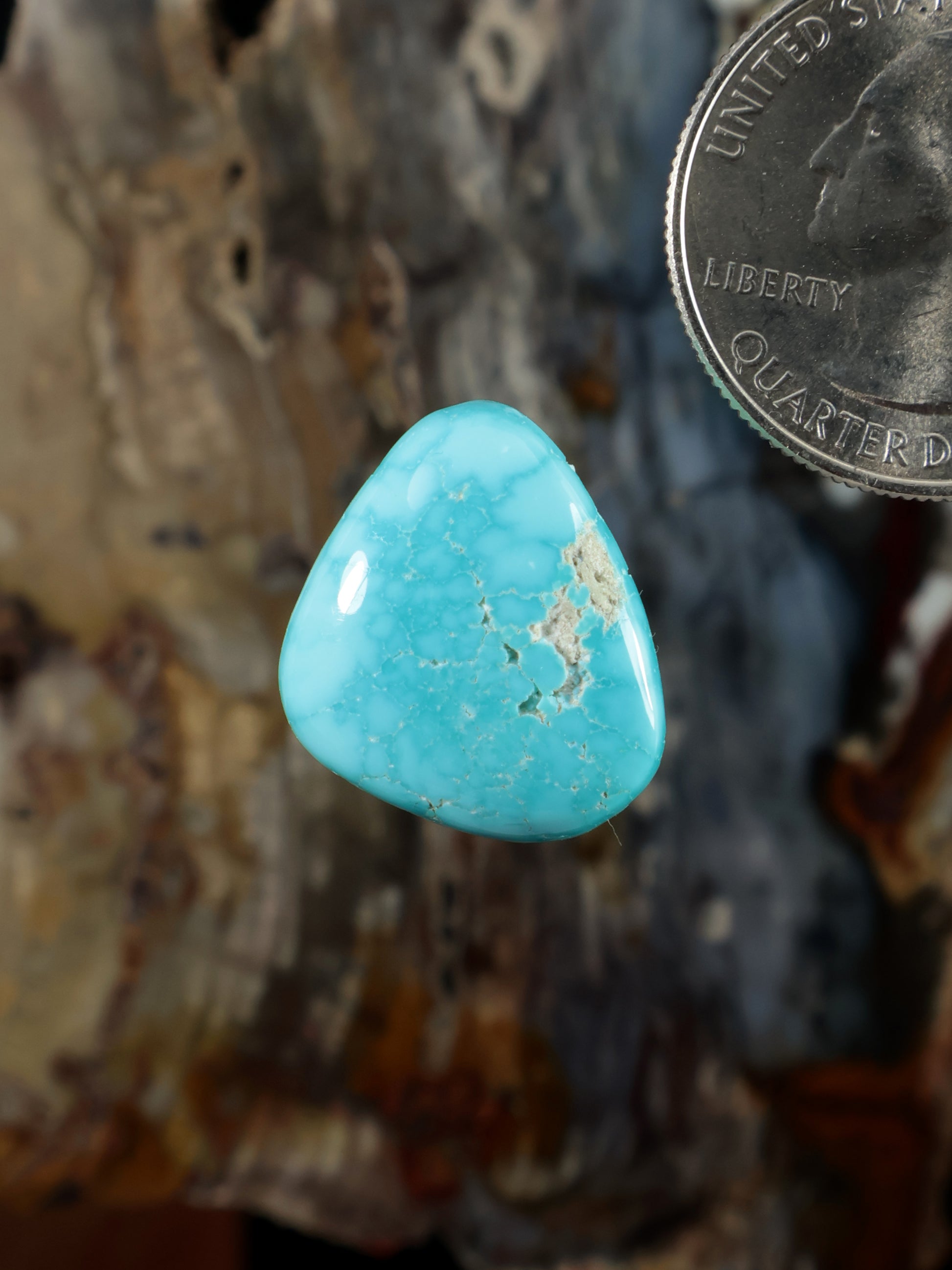 Teardrop turquoise cabochon gemstone with natural matrix veining, polished.