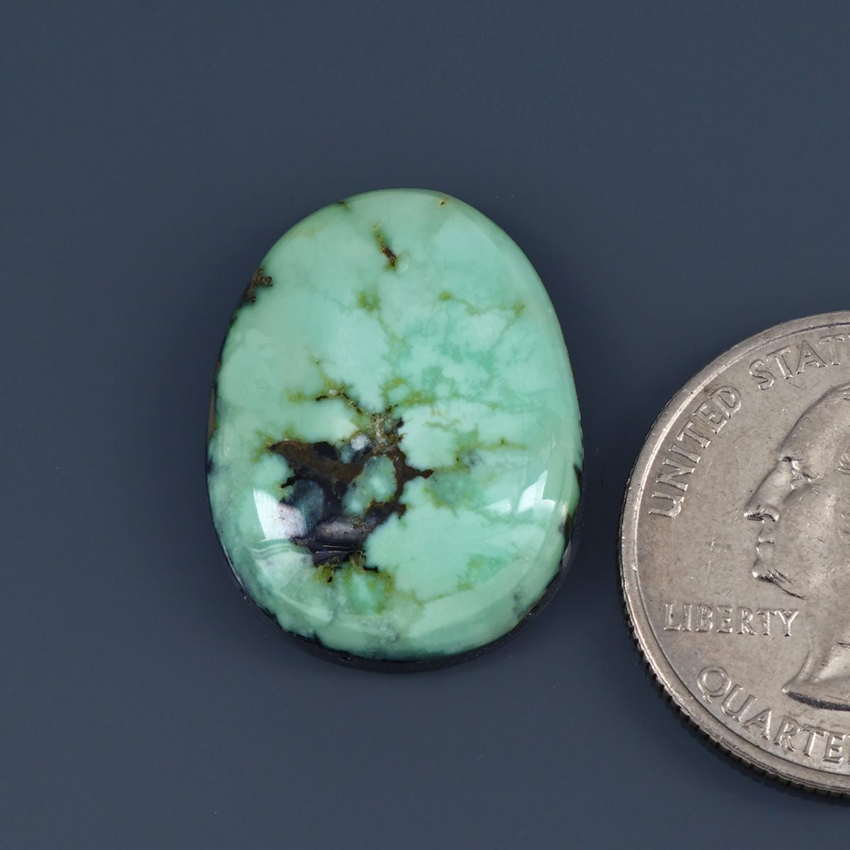 Oval variscite cabochon with polished light green surface and dark web-like veining
