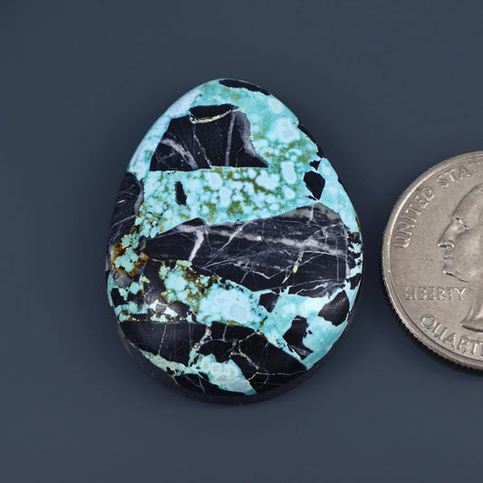 Turquoise cabochon gemstone, oval with black veining and speckles