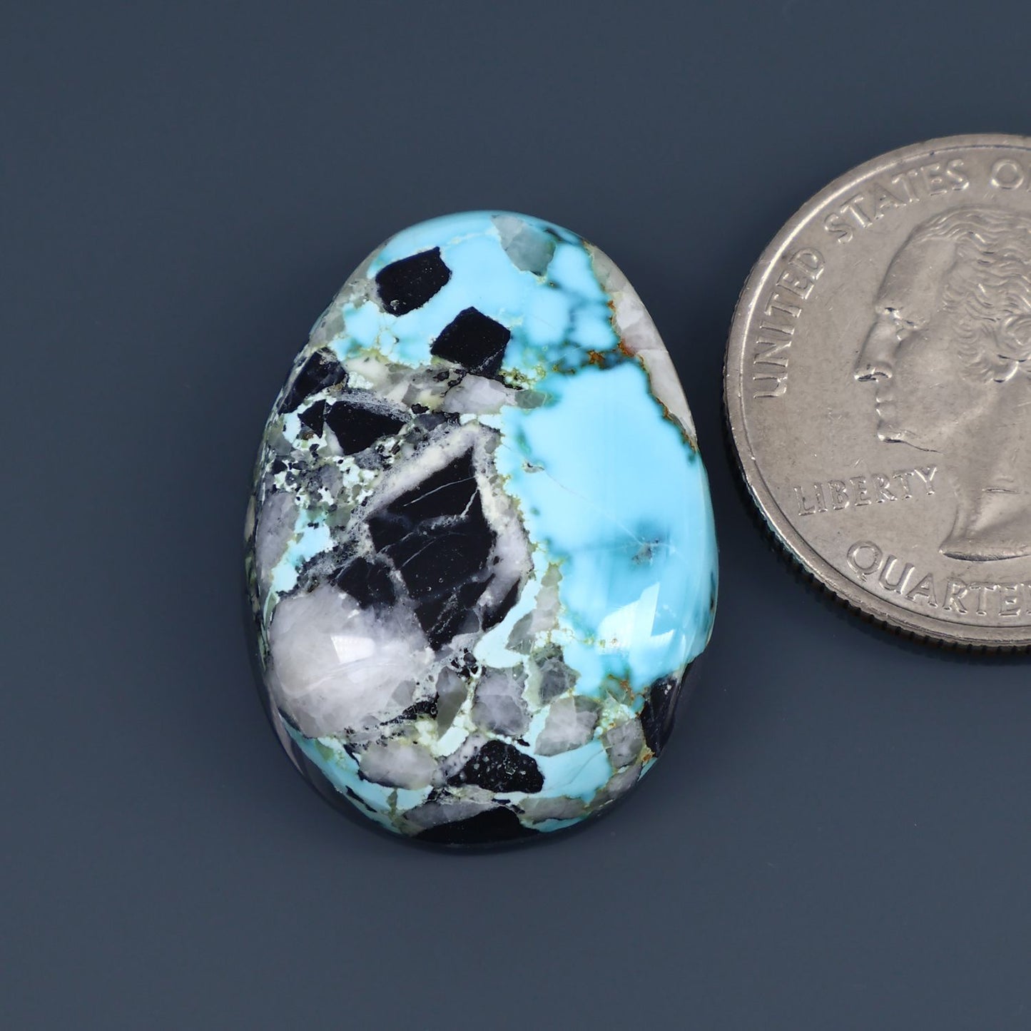 Oval turquoise cabochon gemstone with black matrix and polished shine