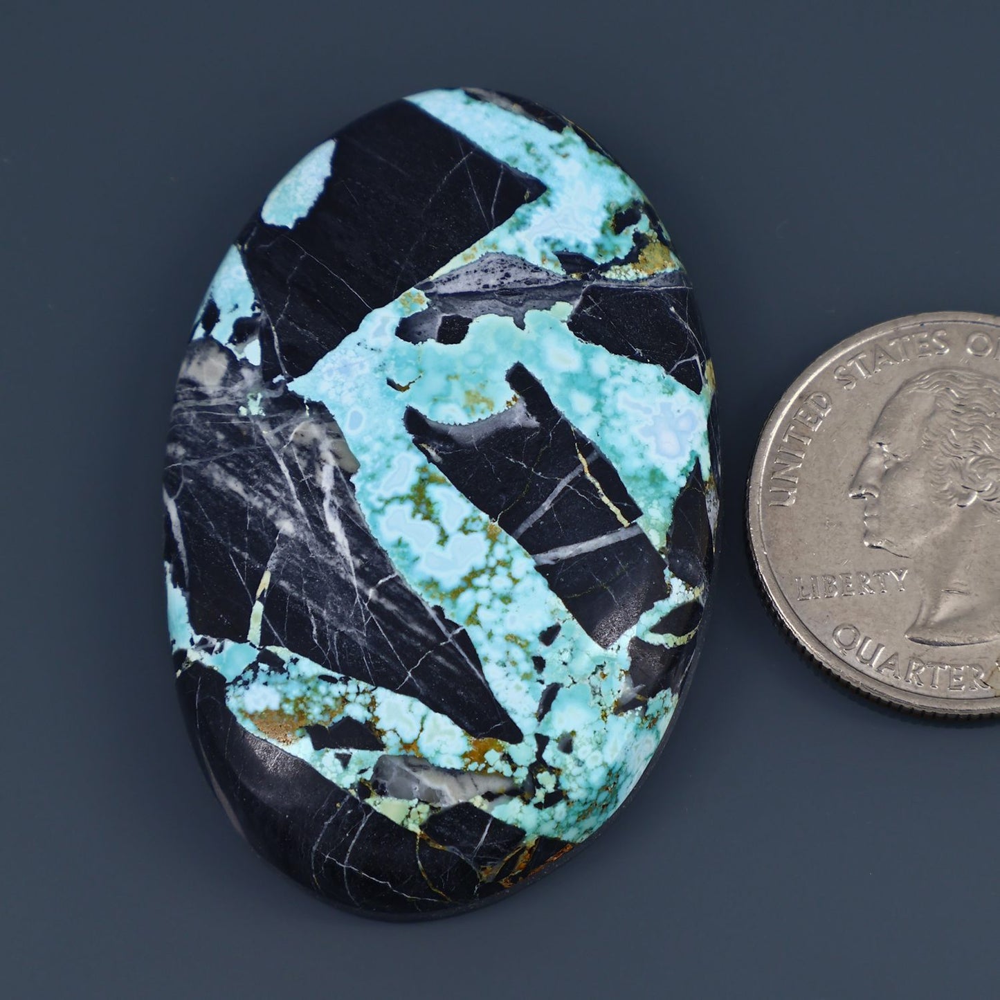 Turquoise and black oval cabochon gemstone with matrix pattern