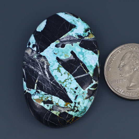 Turquoise and black oval cabochon gemstone with matrix pattern