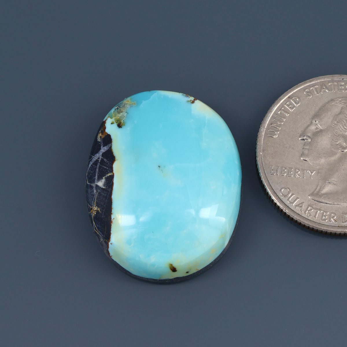 Turquoise cabochon gemstone, oval blue stone with dark matrix edge.