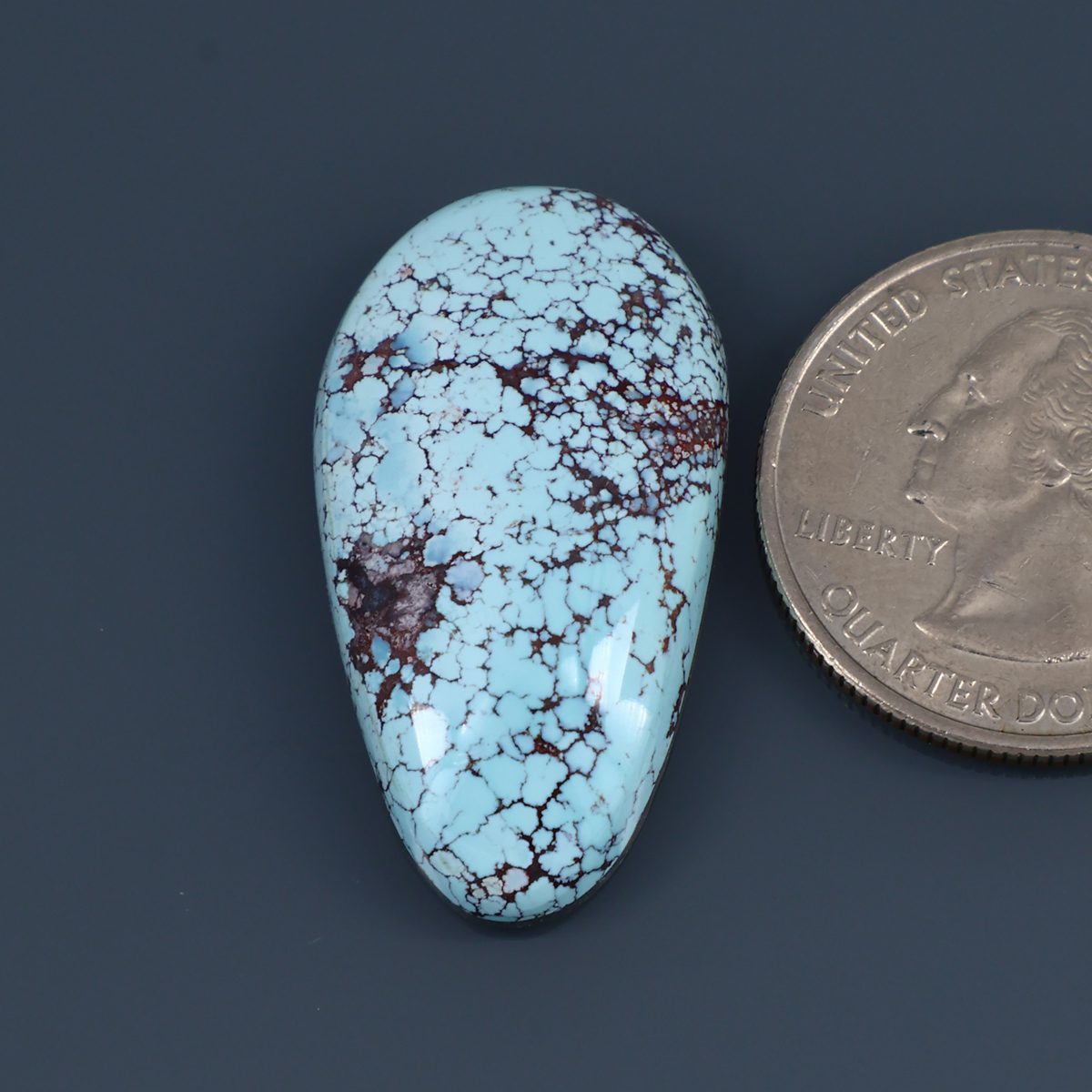 Turquoise cabochon gemstone with white matrix and reddish brown veining, teardrop shape