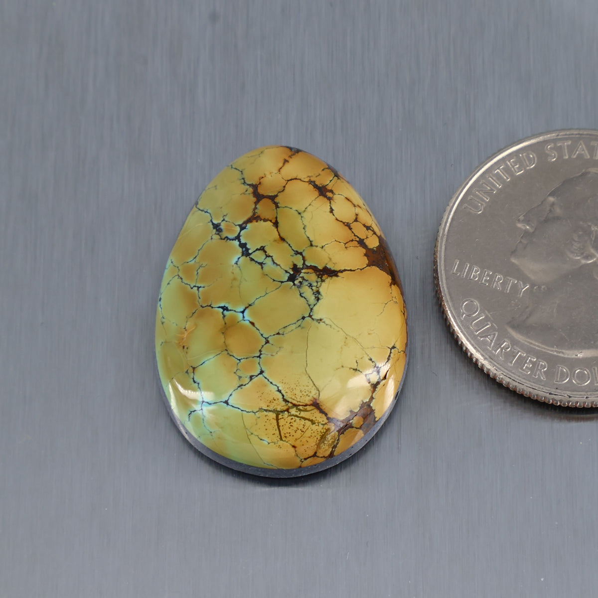 Oval turquoise cabochon with yellow base and webbed dark matrix.