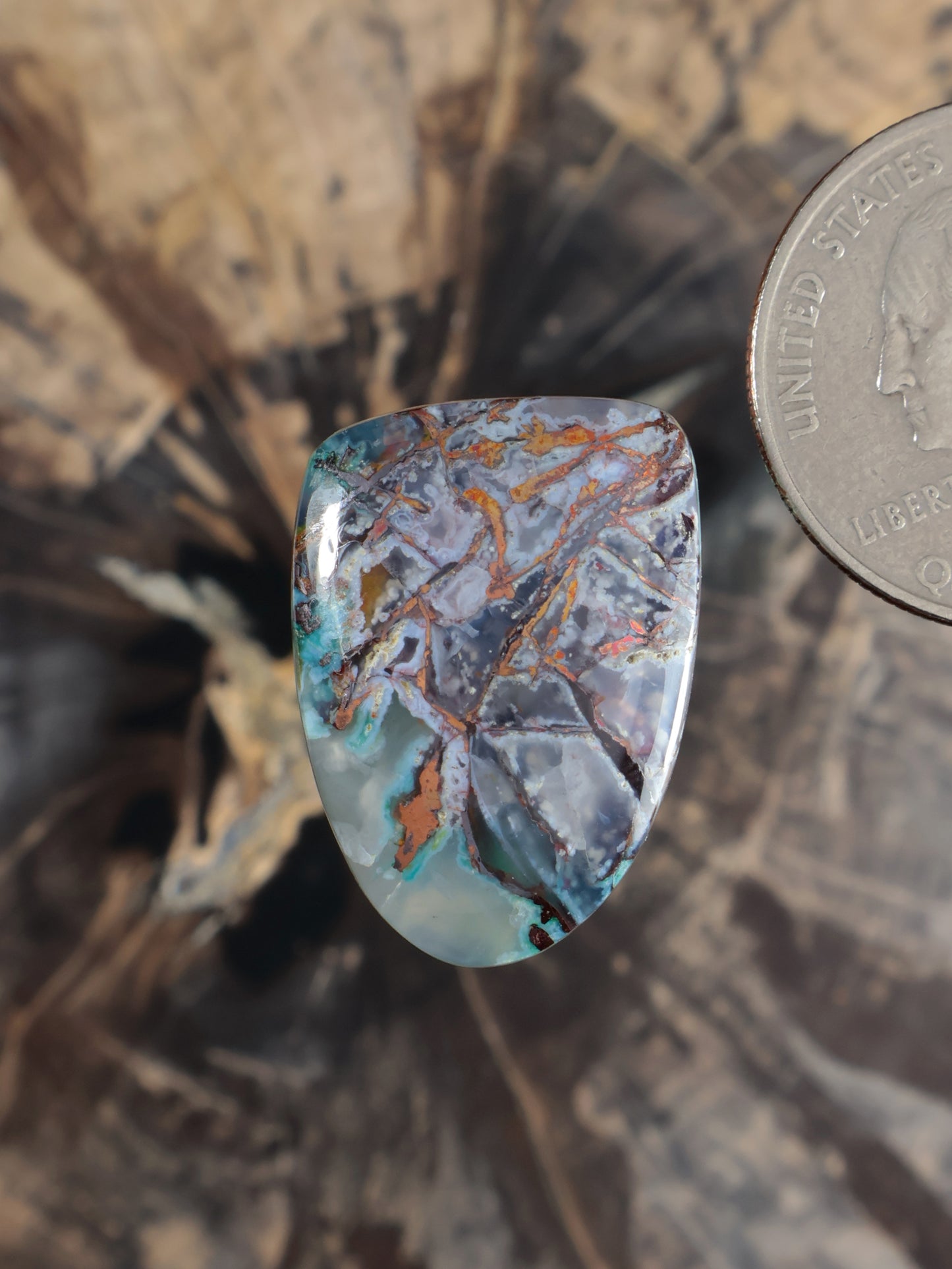 Teal-blue cabochon gemstone with orange copper veining, domed oval shape