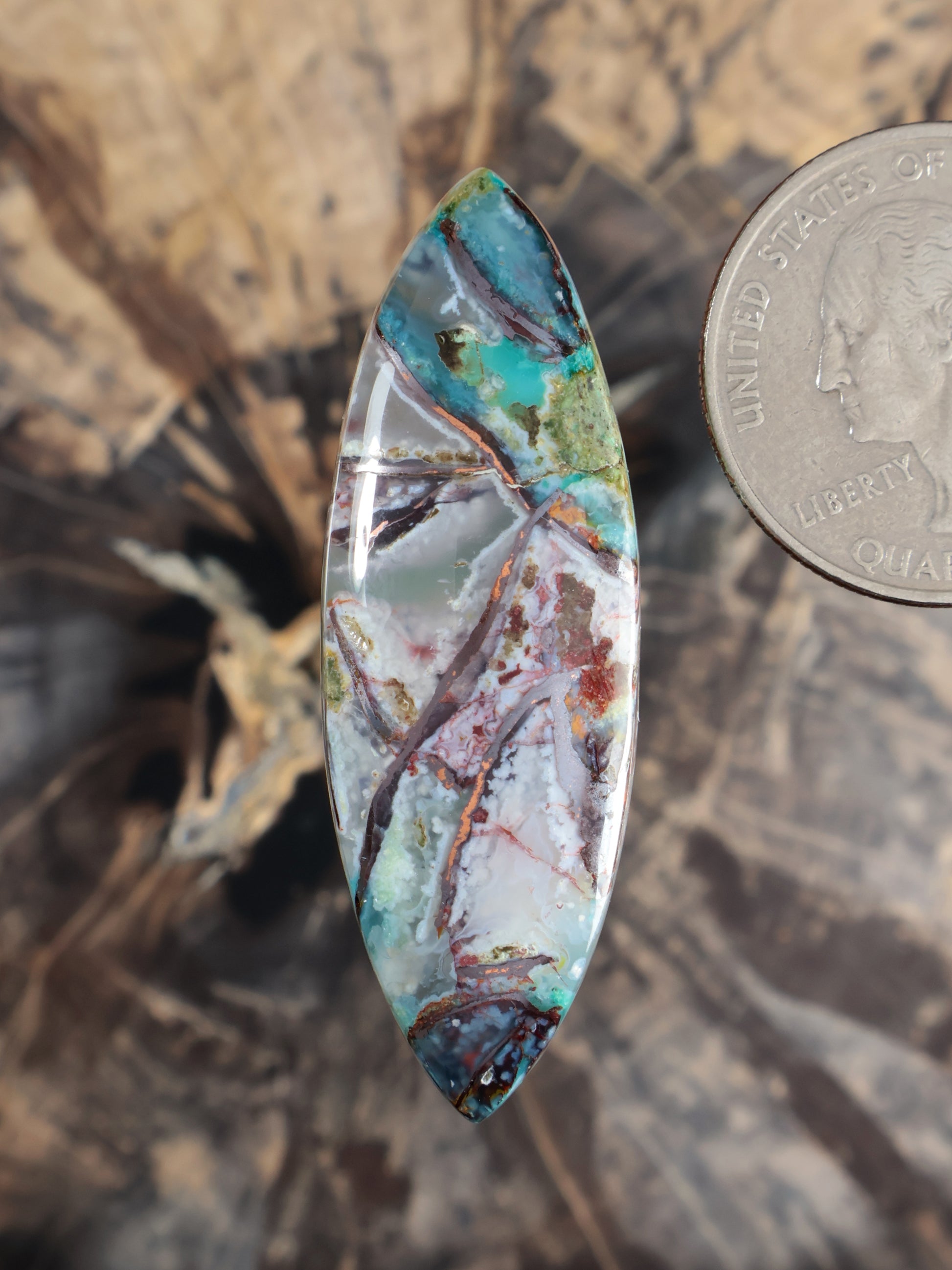 Teardrop cabochon gemstone with turquoise, green, and red matrix, domed surface