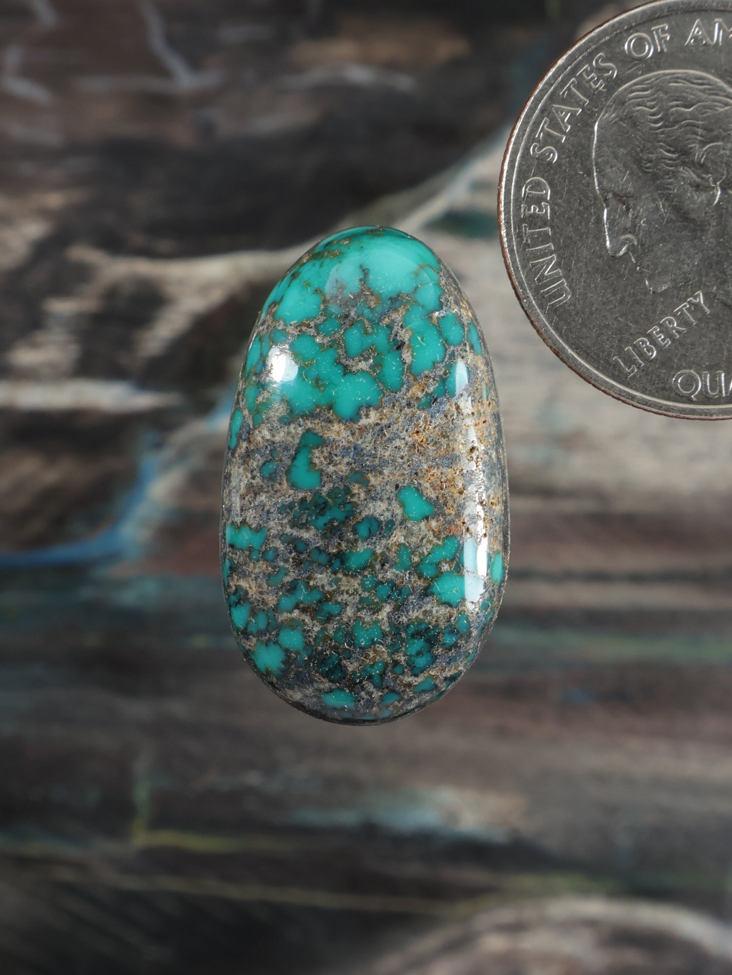 Turquoise cabochon gemstone with oval teardrop shape and blue-green veining.