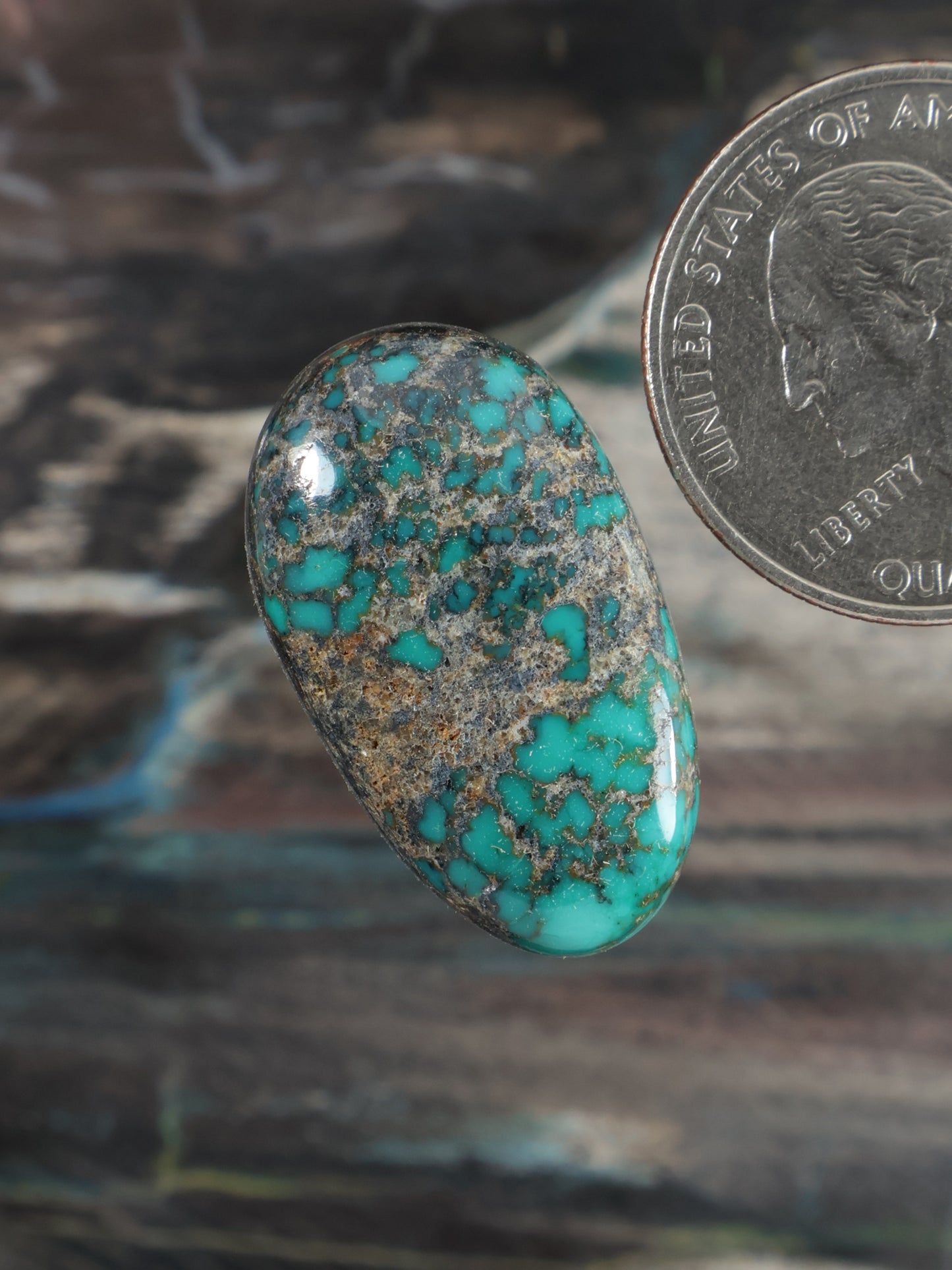 Turquoise cabochon gemstone, oval teardrop with speckled blue-green matrix texture.