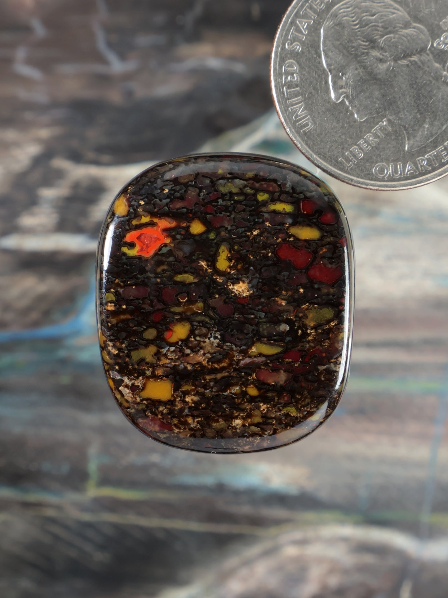 Polished dinosaur gembone cabochon, oval dark amber with orange and yellow flecks