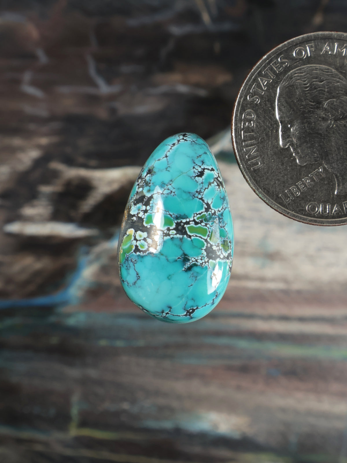 Turquoise cabochon teardrop gemstone with green-gold veining, polished surface