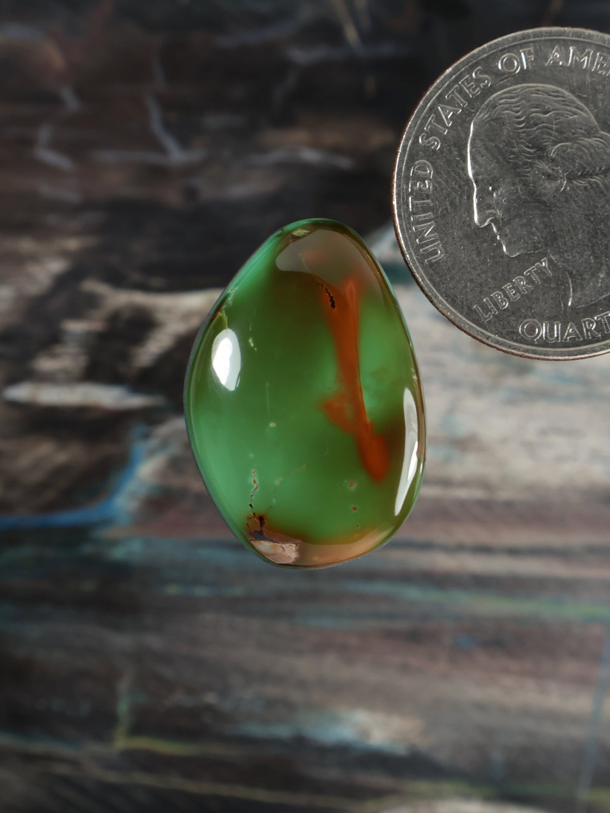 Green teardrop cabochon gemstone with orange matrix inclusions