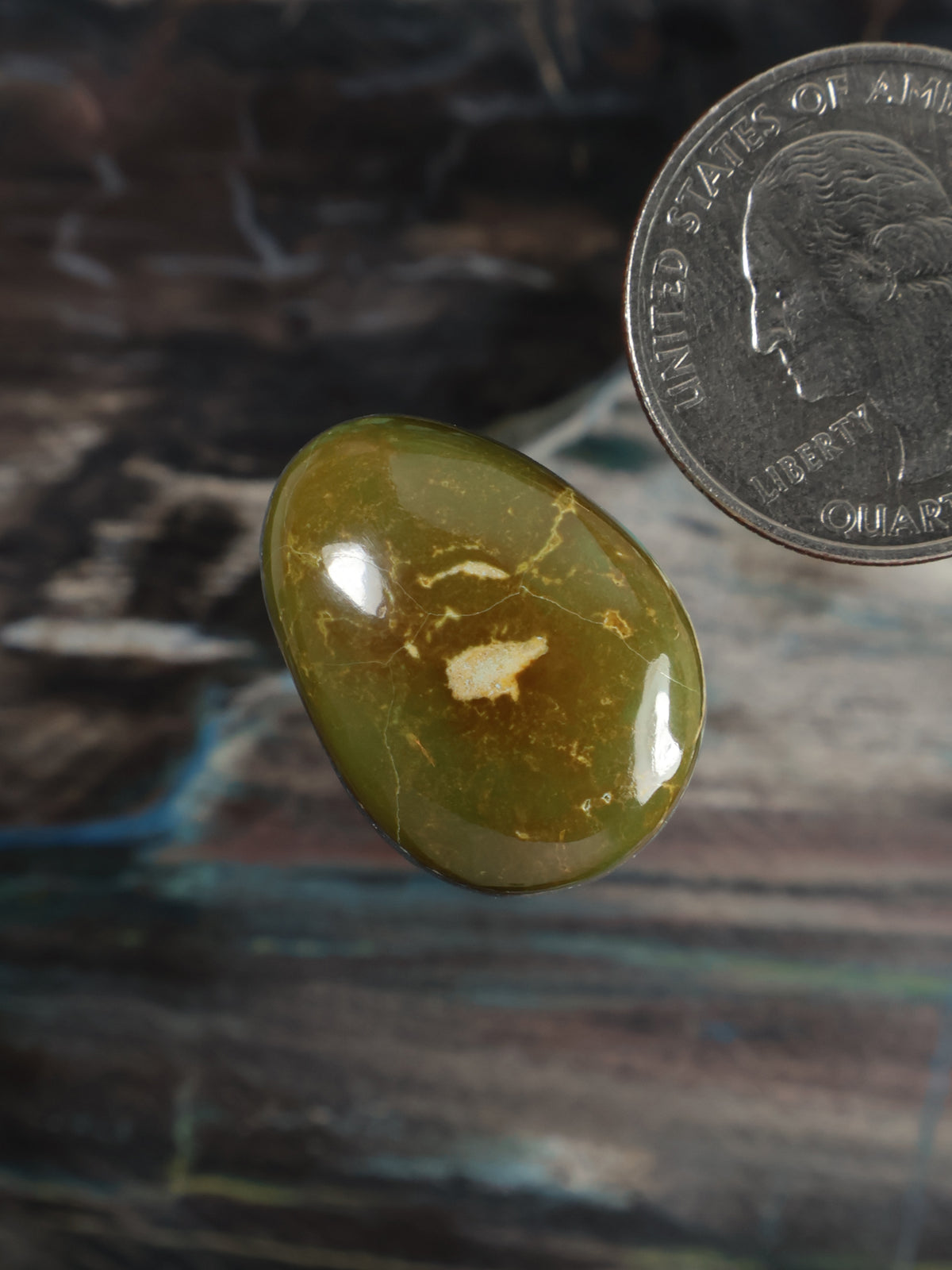 Tilted oval green cabochon gemstone with glossy finish and light veining