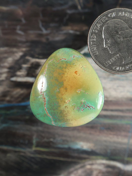 Turquoise cabochon gemstone teardrop, green-blue with yellow matrix and reddish speckles.