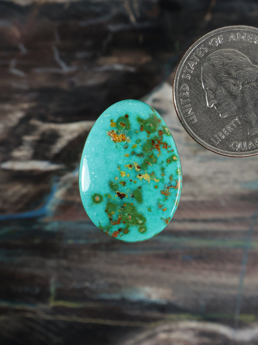 Turquoise oval cabochon with red and gold speckled inclusions