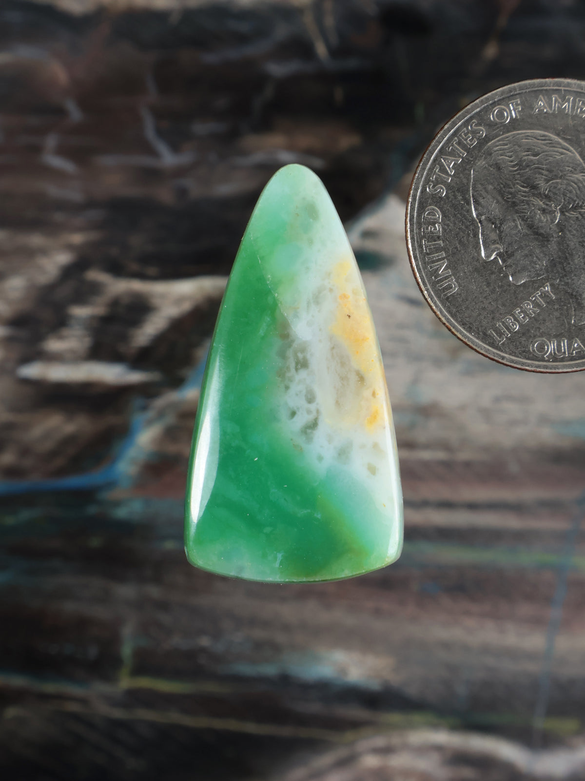 Green teardrop cabochon gemstone with light streaks and yellow specks