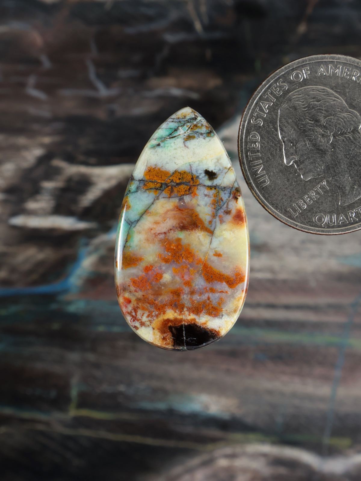 Teardrop petrified wood cabochon with blue, orange, and green opalescent pattern