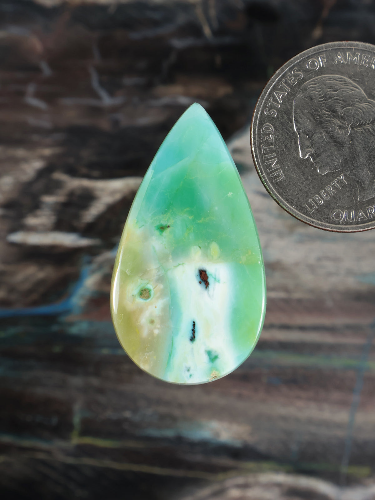 Opalized petrified wood cabochon, teardrop shape, translucent green-blue with dark specks
