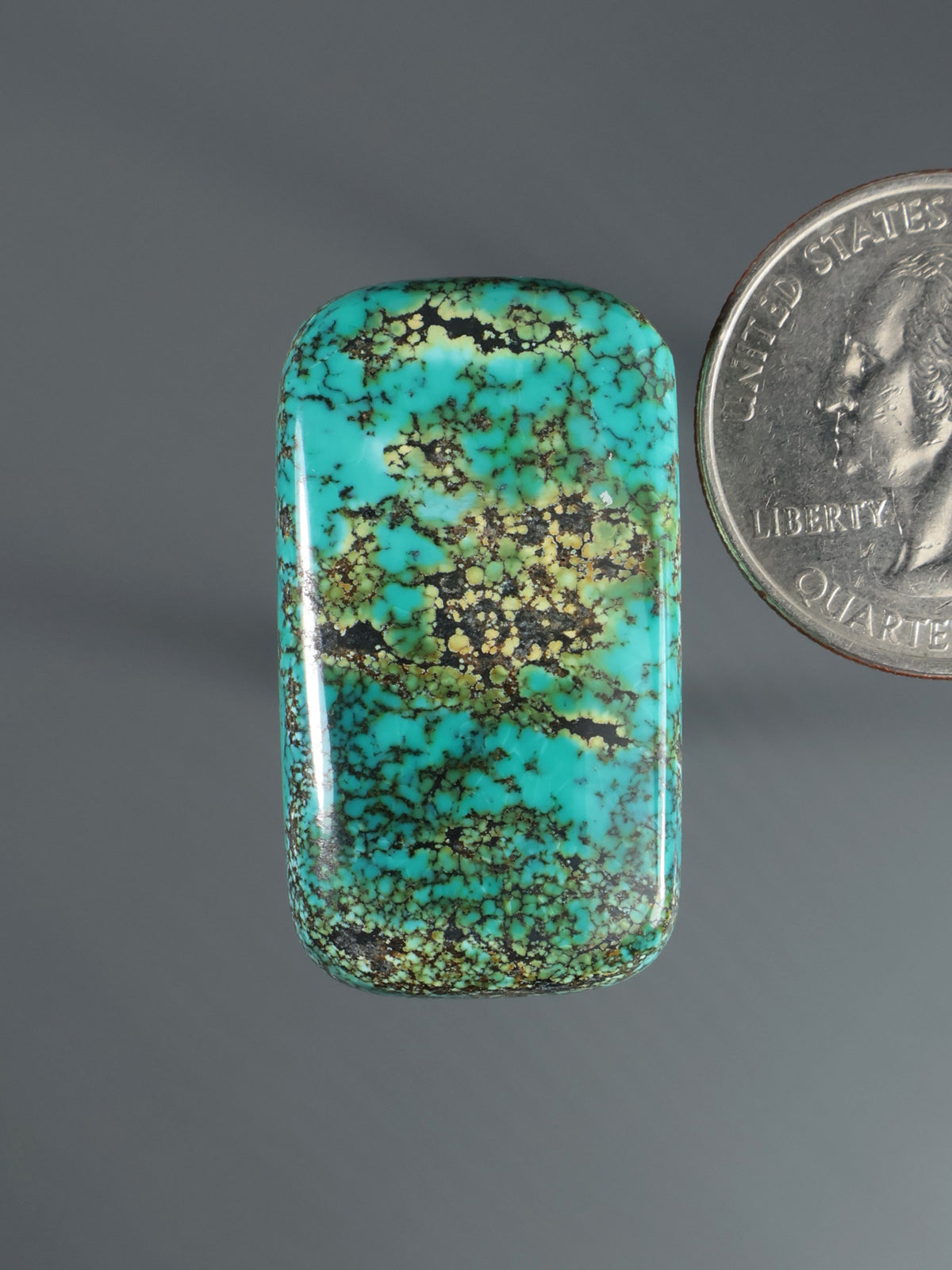 Turquoise-green cabochon gemstone with mottled matrix, oval rectangle shape