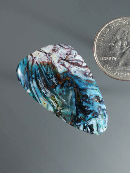 Blue marbled cabochon gemstone, rounded oval with white-red web and streaks