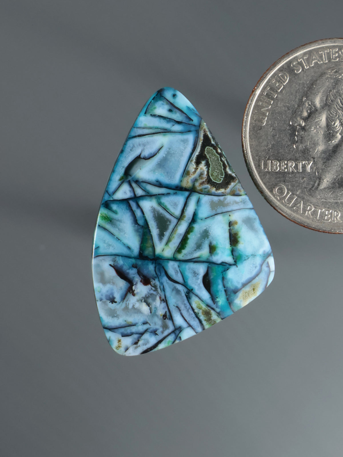 Blue-green marbled teardrop cabochon gemstone with dark matrix veining