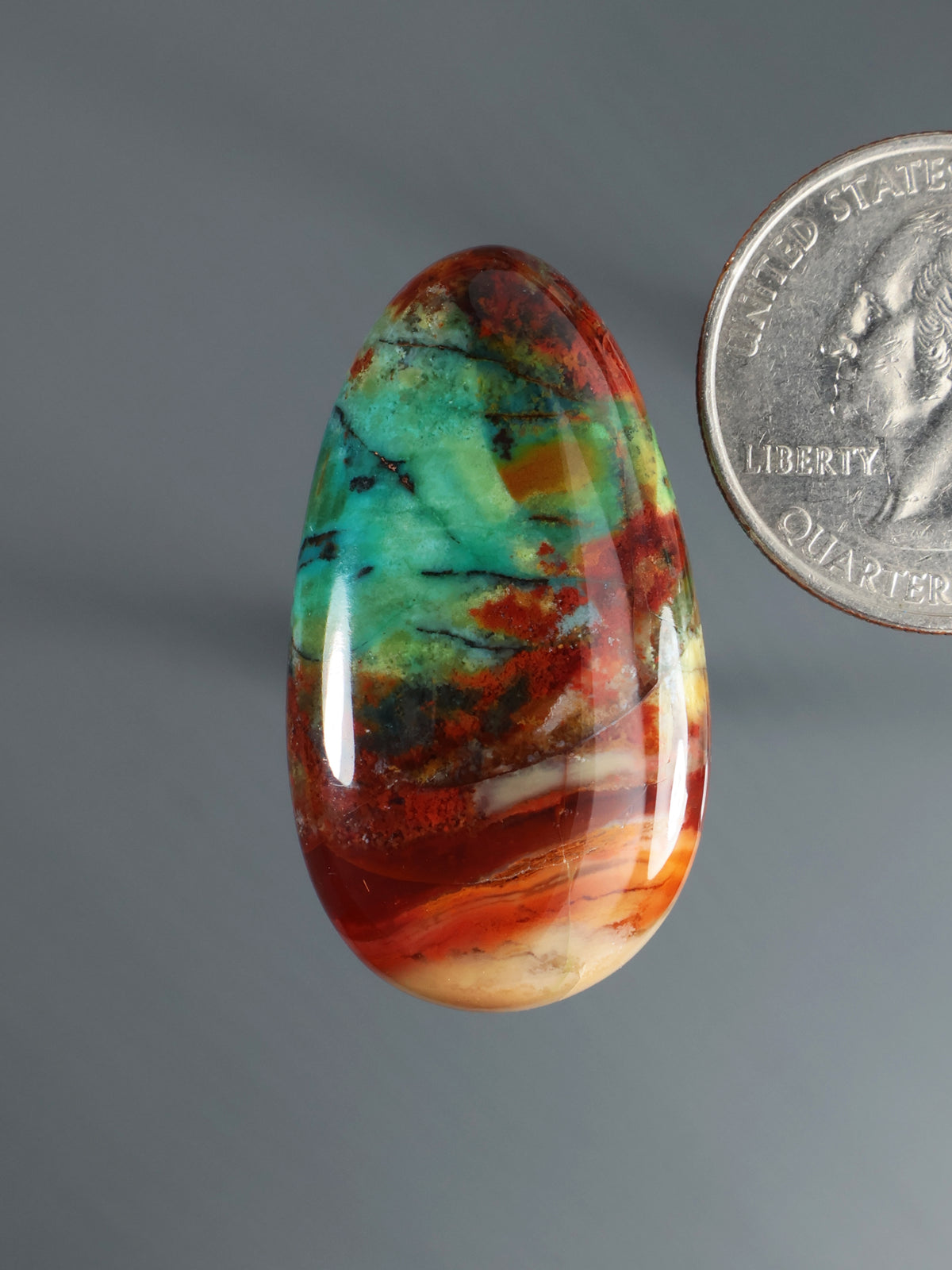 Multicolor oval cabochon gemstone with red orange green and blue swirls